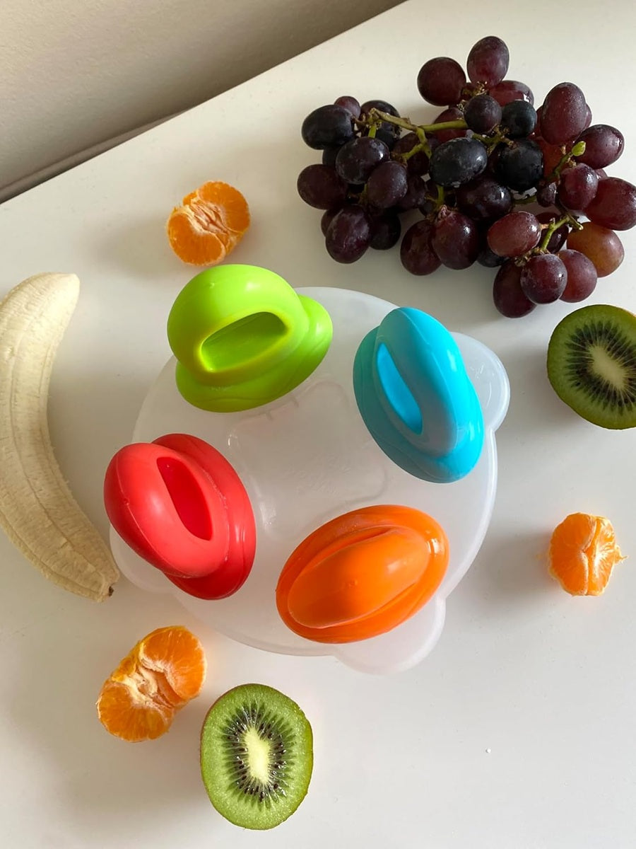 Biała taca Nuby Fruitsicles z czterema kolorowymi uchwytami przy bananie, winogronach, kiwi i mandarynce.