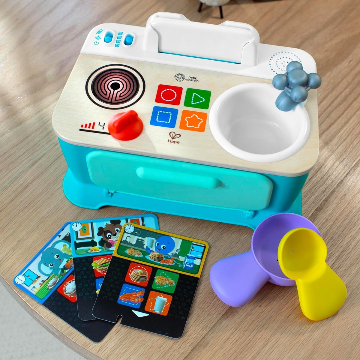 Kuchnia Baby Einstein Hape widziana z góry, z garnkiem, łyżką i rozłożonymi kartami.
