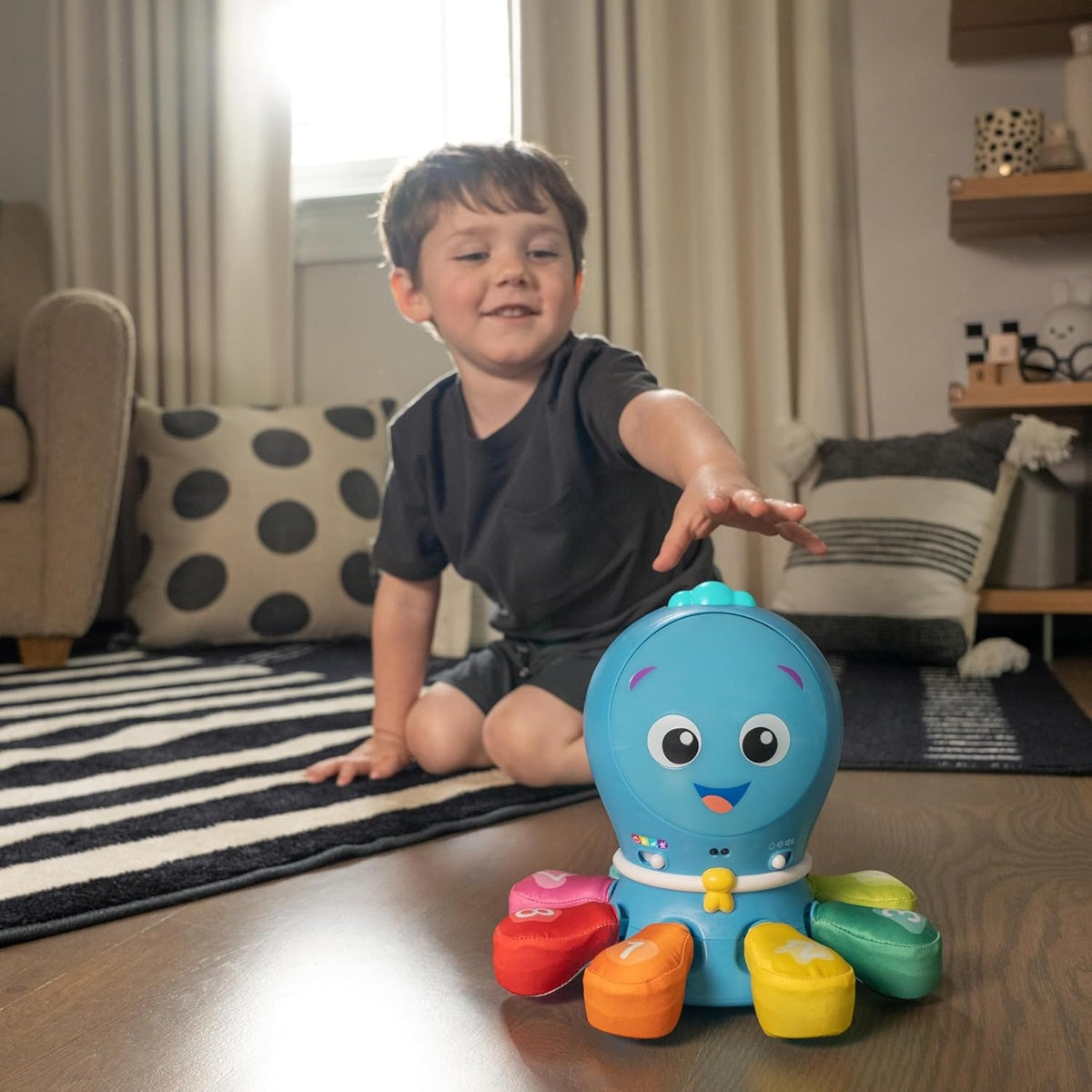 Chłopiec siedzący przy dywanie i sięgający do ośmiornicy Baby Einstein Ocean Explorers.